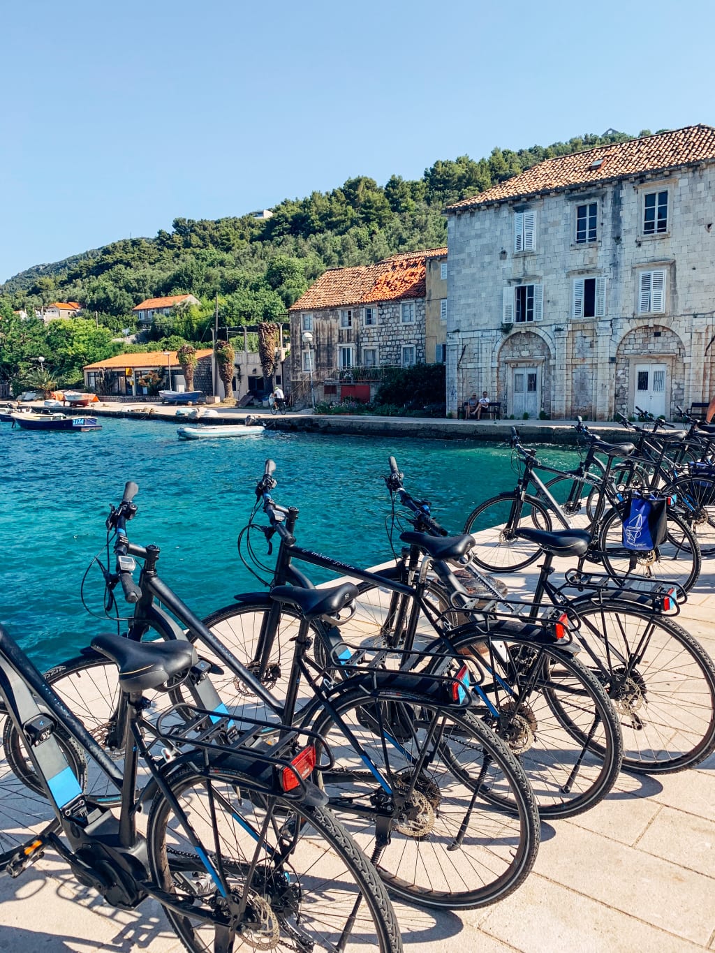Biciclette parcheggiate lungo una strada costiera in un villaggio sul mare, Croazia, Dalmazia bici e barca